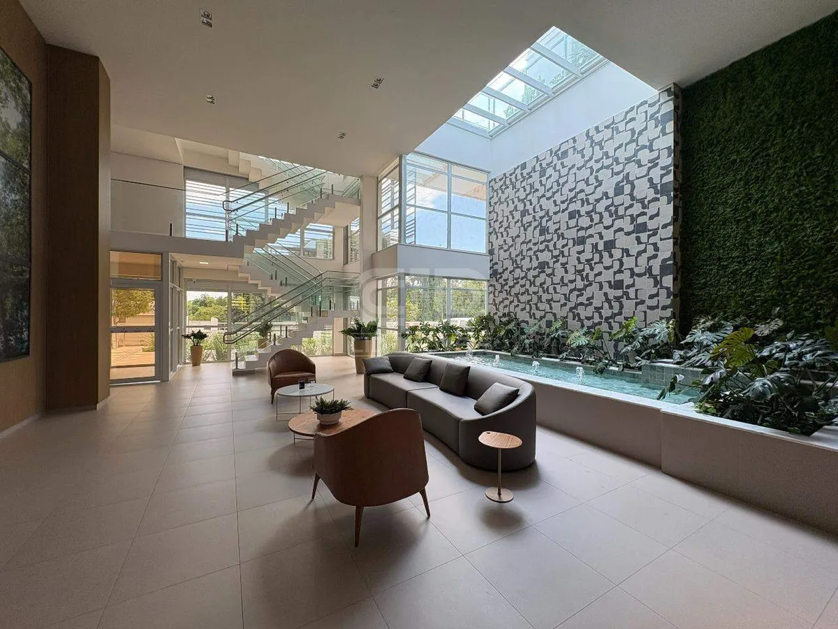Lobby do condomínio com jardim vertical, claraboia e espelho d'água
